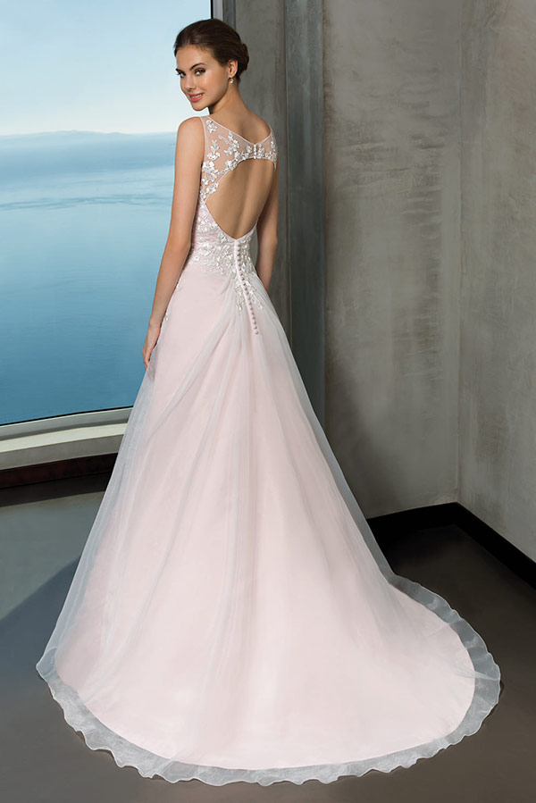 Junge Frau lächelt ruhig in weißem Brautkleid mit Rückenausschnitt und Spitze