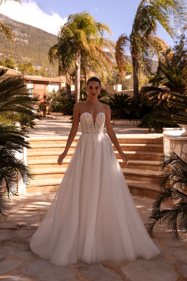 Eine junge Frau in einem eleganten weißen Brautkleid steht selbstbewusst im Freien