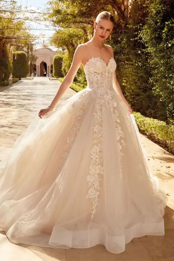 Eine junge Frau mit elegantem Lächeln trägt ein cremefarbenes Spitzenkleid im Garten