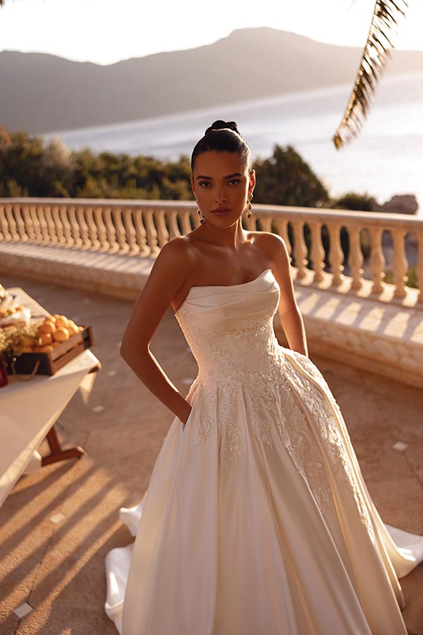 Eine elegant gekleidete Frau im weißen Brautkleid blickt ernst in die Kamera
