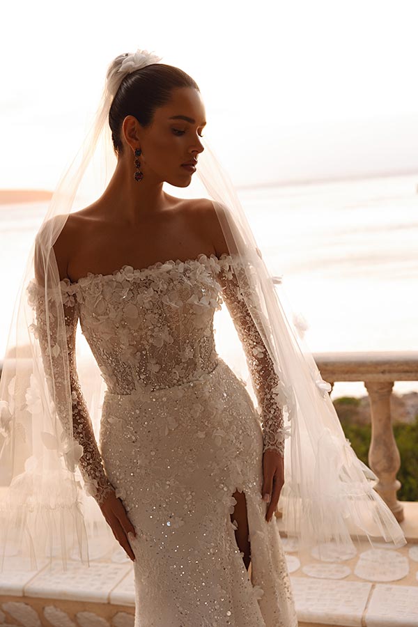 Eine elegante Frau mit ernstem Blick trägt ein funkelndes Brautkleid in Weiß