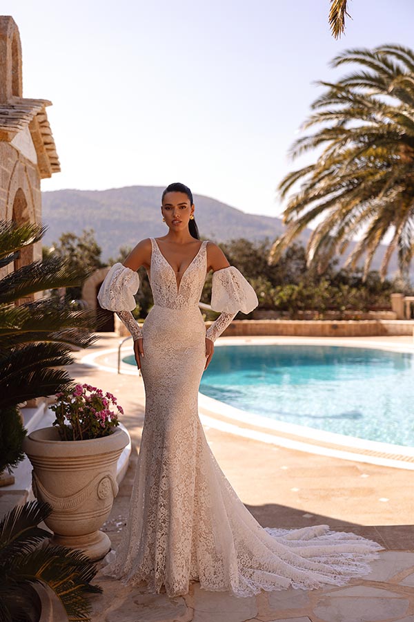 Eine Frau mit ernstem Blick trägt ein elegantes weißes Spitzenkleid am Pool