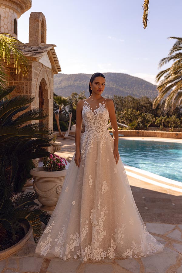 Eine junge Frau mit ernstem Blick trägt ein cremefarbenes Spitzenkleid am Pool