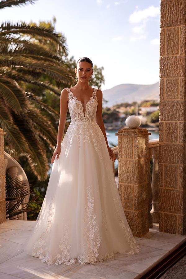 Junge Frau in elegantem weißen Hochzeitskleid mit floralen Spitzen und ernstem Blick