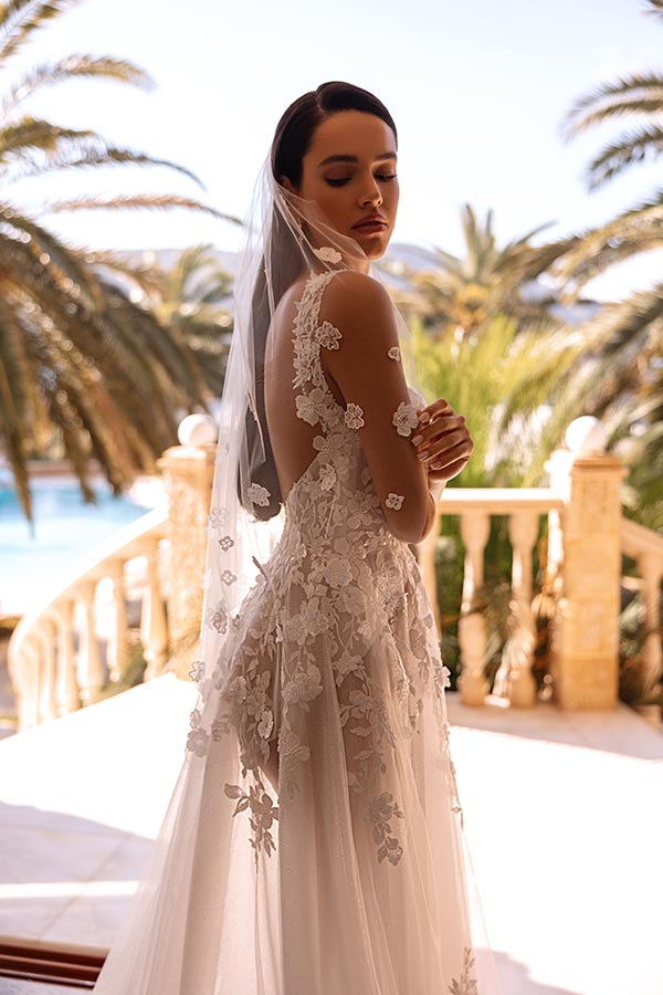 Eine junge Frau in einem eleganten weißen Brautkleid schaut verträumt zur Seite