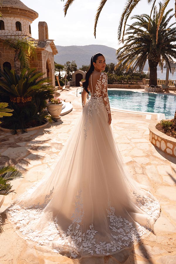 Eine Frau mit ernstem Blick trägt ein elegantes weißes Kleid mit Spitze am Pool