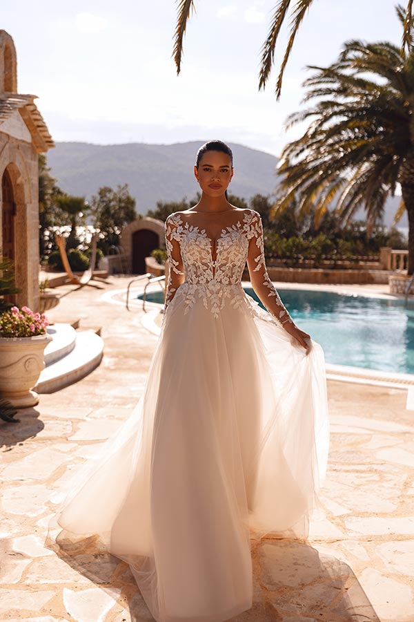 Eine junge Frau mit ernstem Gesichtsausdruck trägt ein elegantes Brautkleid mit Spitze