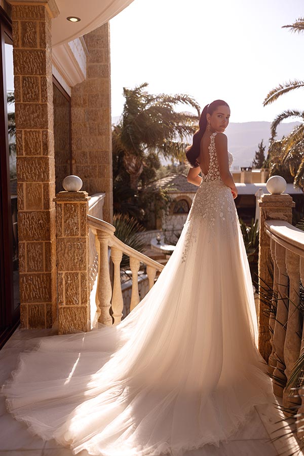 Eine Frau mit ernstem Ausdruck trägt ein weißes Brautkleid auf einem sonnigen Balkon