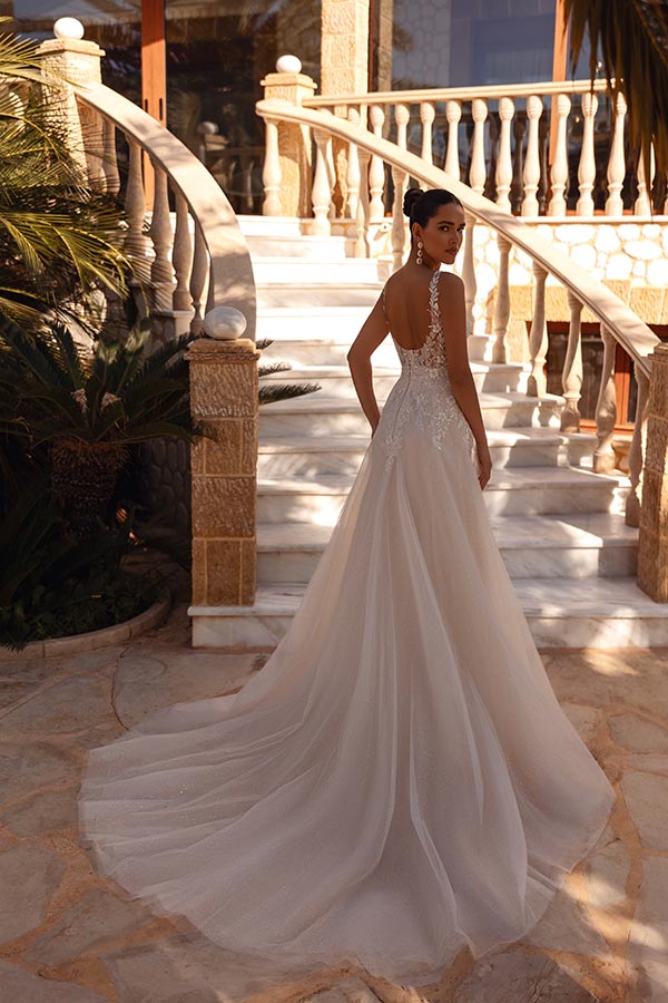 Eine Frau mit elegantem Gesichtsausdruck trägt ein weißes Brautkleid mit langer Schleppe