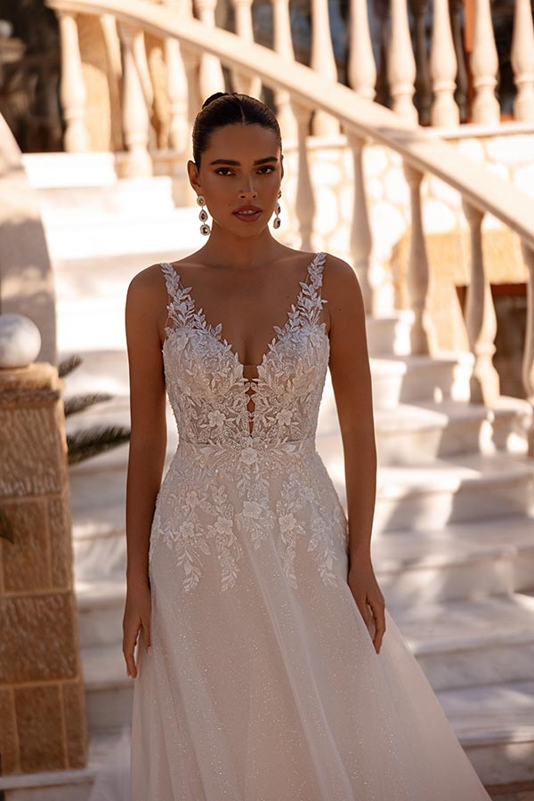 Eine Frau mit ernstem Blick trägt ein elegantes, besticktes, weißes Brautkleid