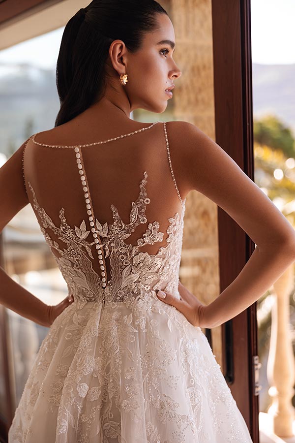 Junge Frau mit ernster Miene im weißen Spitzenkleid mit transparentem Rückenteil