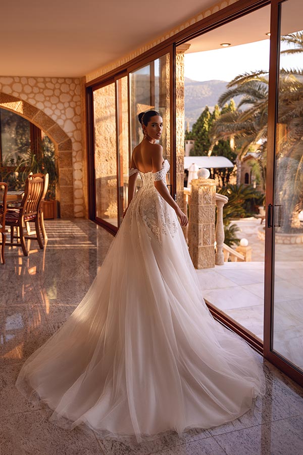 Eine elegant gekleidete Frau in einem weißen Brautkleid blickt verträumt zurück