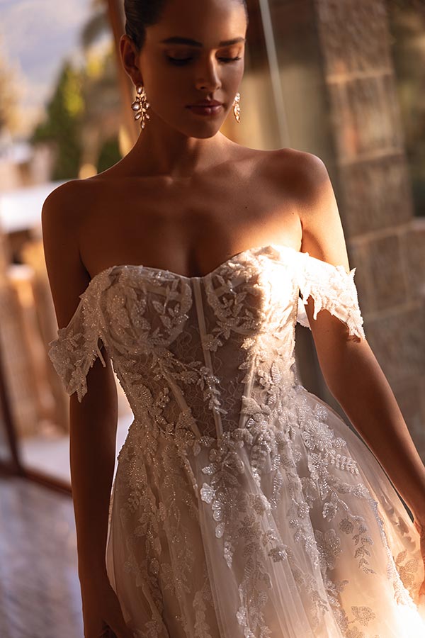 Eine Frau mit entspanntem Gesichtsausdruck trägt ein elegantes cremefarbenes Spitzenkleid