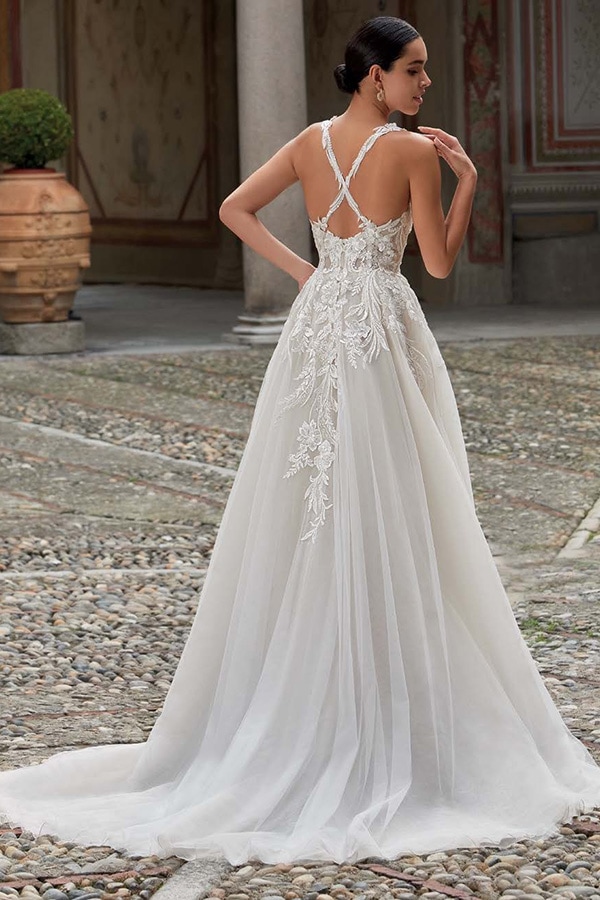 Eine Frau im eleganten weißen Spitzenkleid blickt mit ruhigem Gesichtsausdruck zurück