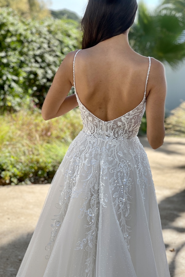 Eine Frau mit langen braunen Haaren trägt ein elegantes weißes Spitzenkleid im Garten