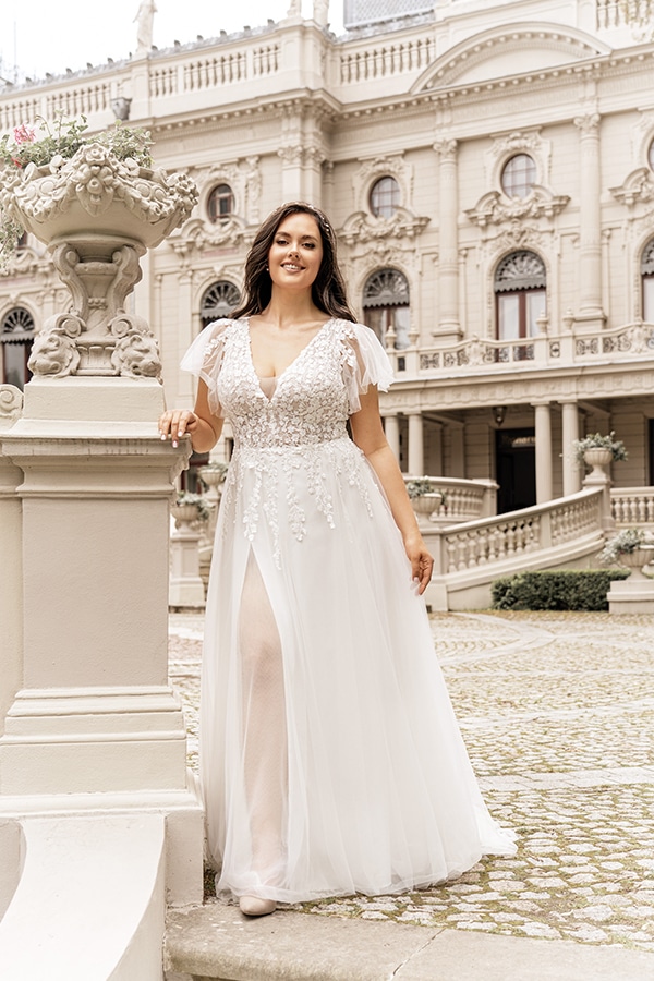 Lächelnde Frau in weißem Brautkleid steht vor einem historischen Gebäude