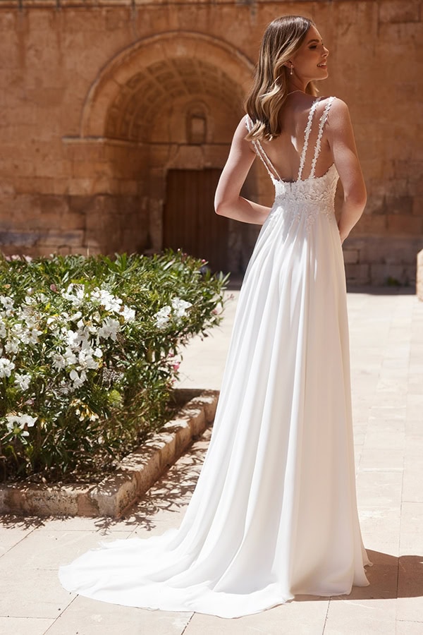 Eine lächelnde Frau mit blondem Haar trägt ein weißes Spitzenkleid im Sonnenschein