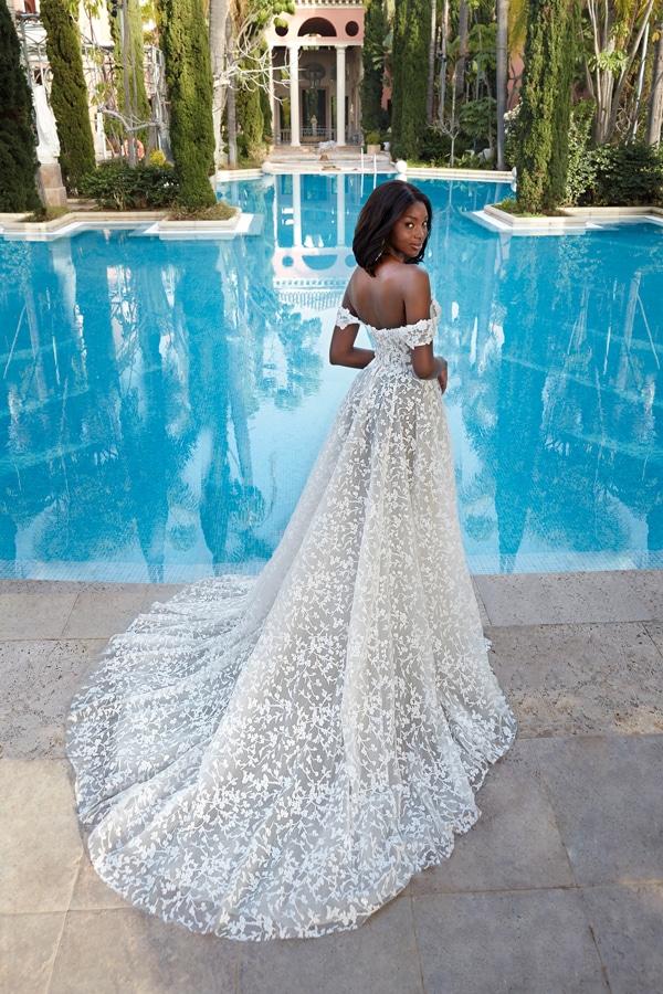 Eine Frau mit eleganter offener Schulterkleidung blickt ernst am Pool über die Schulter