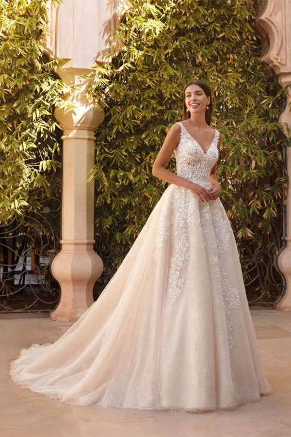 Junge Frau im eleganten weißen Brautkleid lächelt strahlend im Garten