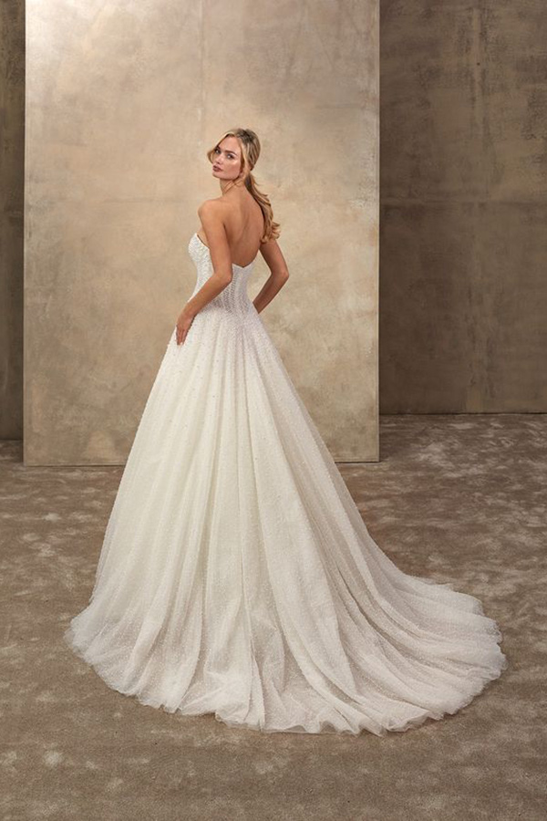 Junge Frau in weißem trägerlosen Brautkleid mit Schleppe und entspannter Miene