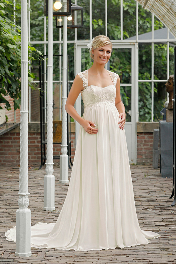 Eine blonde Frau mit freundlichem Gesichtsausdruck trägt ein elegantes cremeweißes Brautkleid
