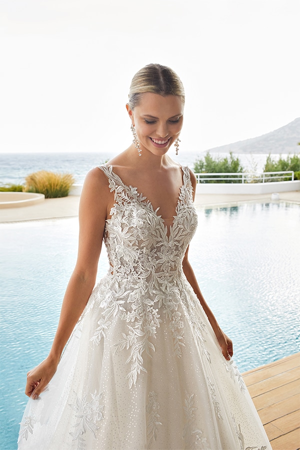 Junge Frau mit elegantem weißen Brautkleid und Spitzenmuster lächelt am Pool