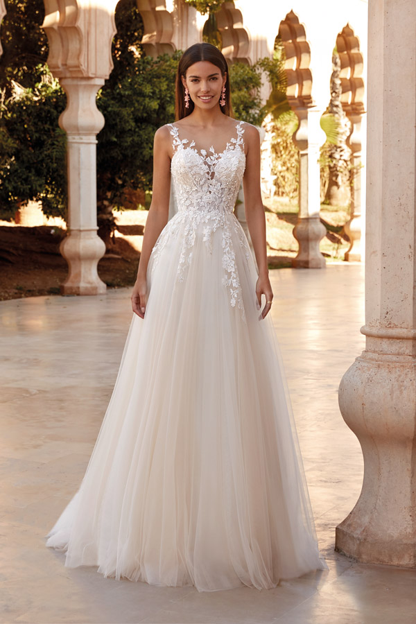 Eine junge Frau lächelt freundlich in einem eleganten cremefarbenen Brautkleid mit Spitze