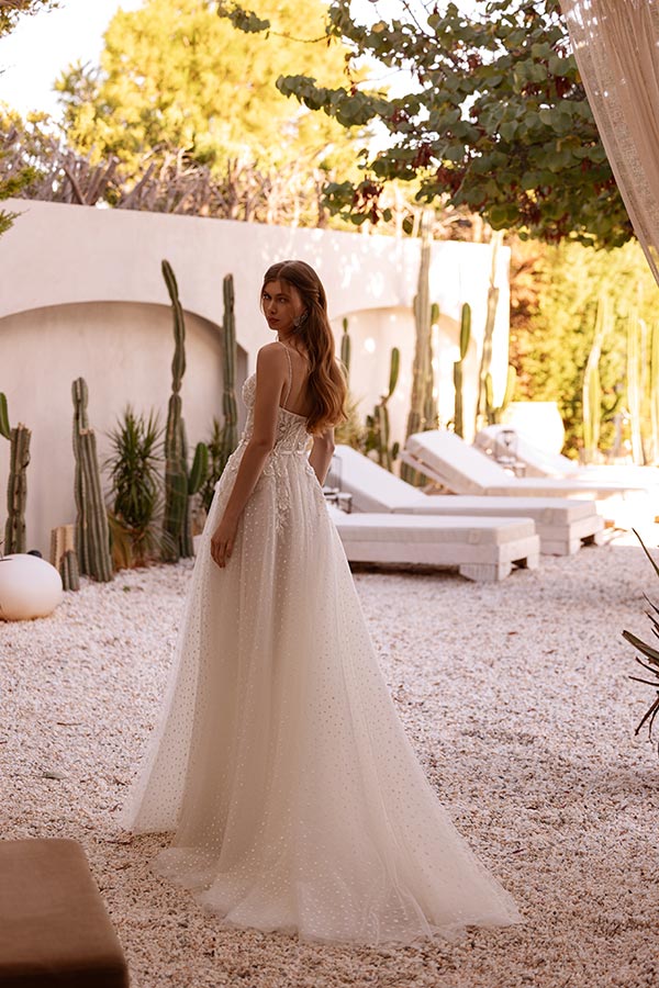 Eine junge Frau im cremefarbenen Brautkleid blickt verträumt über die Schulter