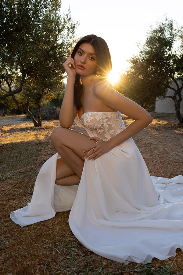 Junge Frau im weißen Brautkleid sitzt elegant auf dem Boden mit nachdenklichem Blick