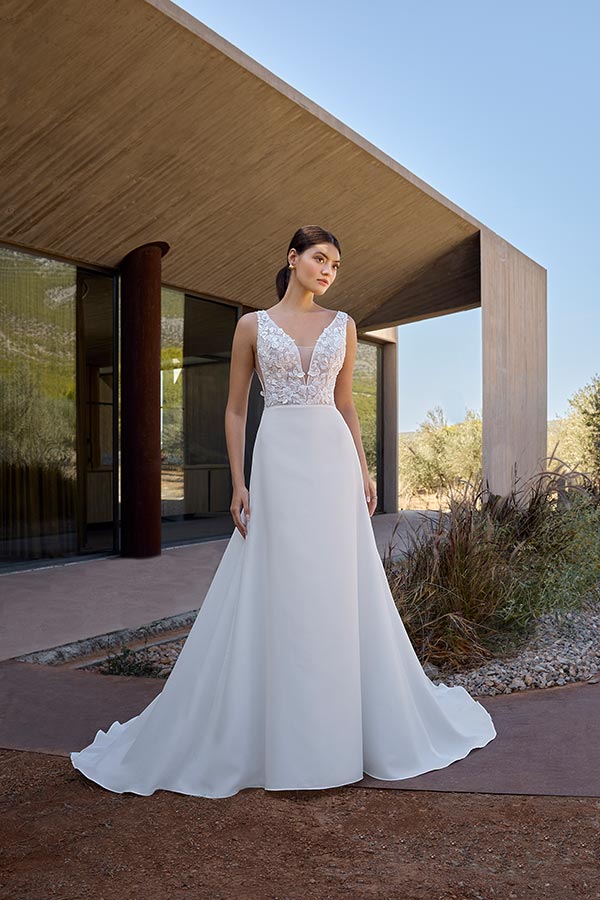 Eine junge Frau mit ernstem Blick trägt ein weißes Brautkleid mit Spitzenoberteil