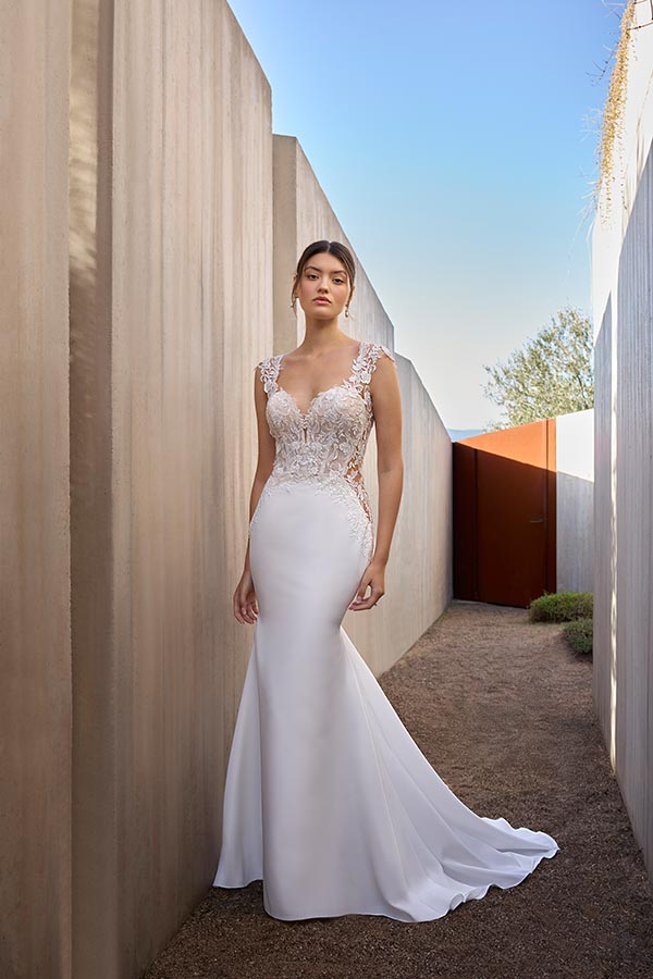 Junge Frau mit ernstem Blick trägt ein elegantes weißes Brautkleid im Freien
