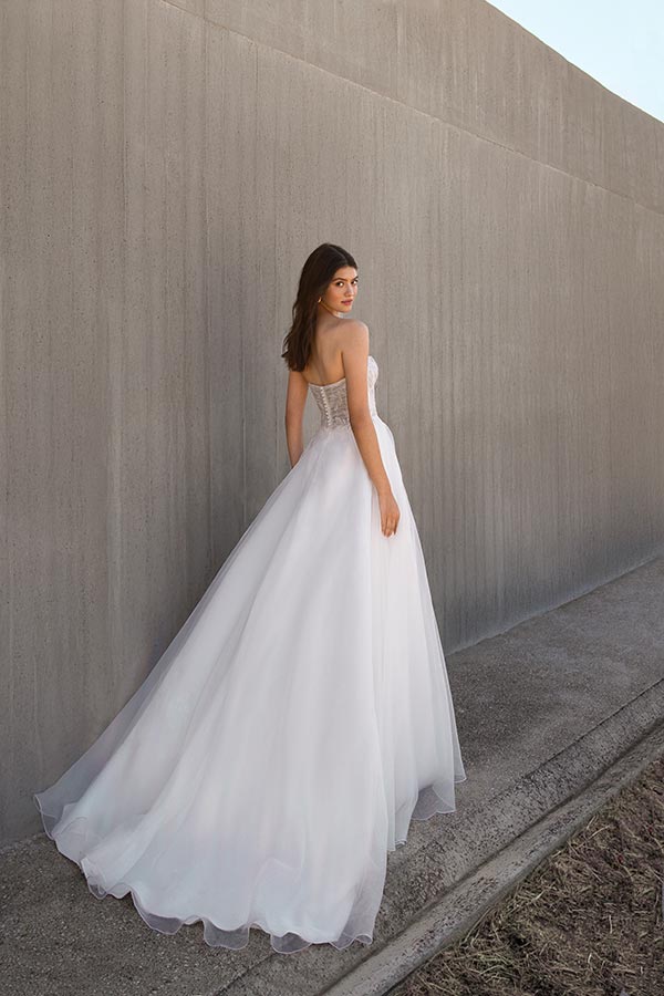Eine junge Frau mit langen braunen Haaren trägt ein elegantes weißes Brautkleid