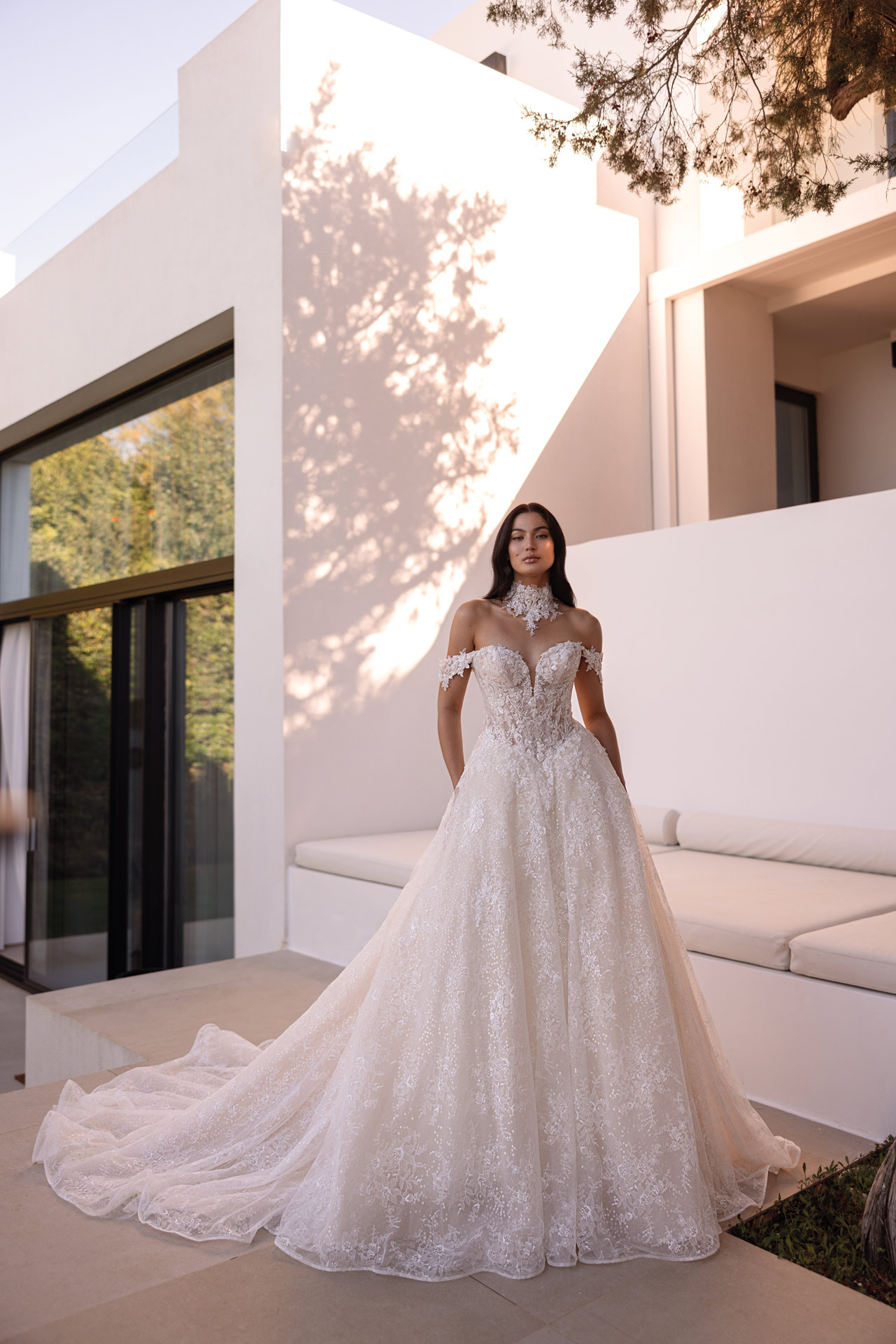 Frau mit dunklem Haar in elegantem weissem Spitzenbrautkleid mit langer Schleppe