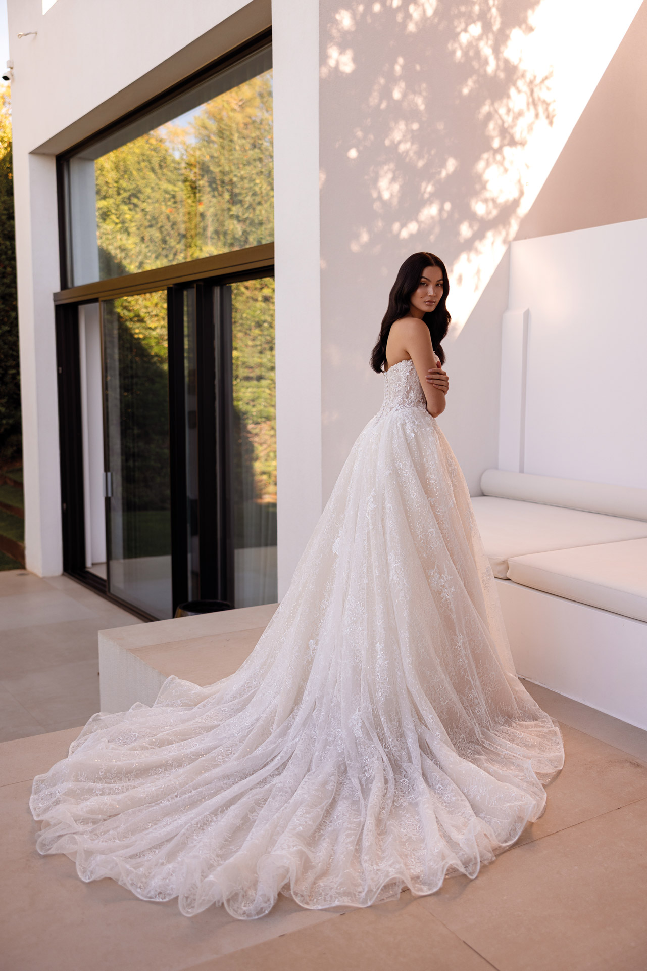 Junge Frau in elegantem weissen Brautkleid mit langer Schleppe
