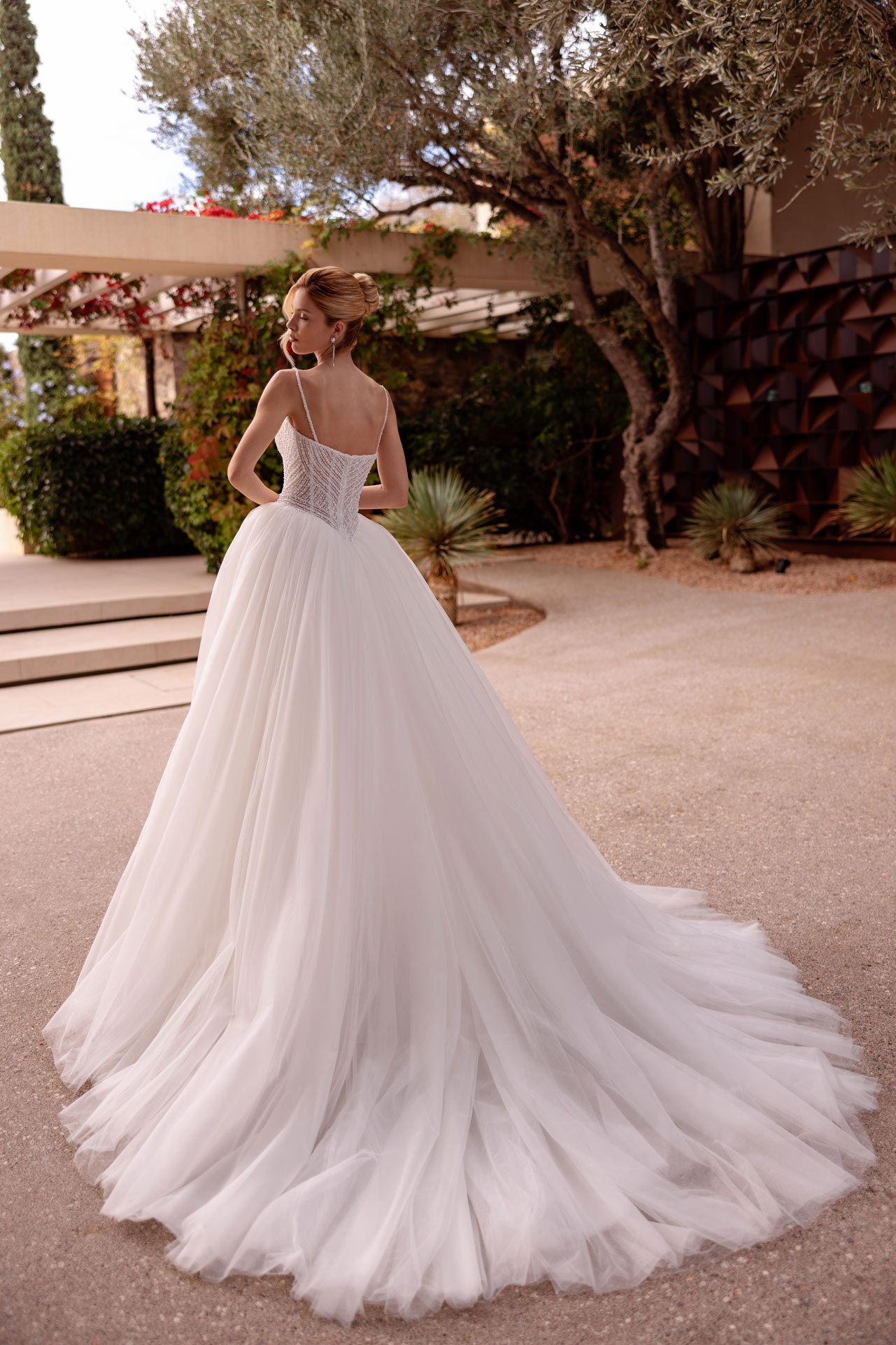 Junge Frau im weissen Brautkleid mit Tuellrock von hinten im Garten