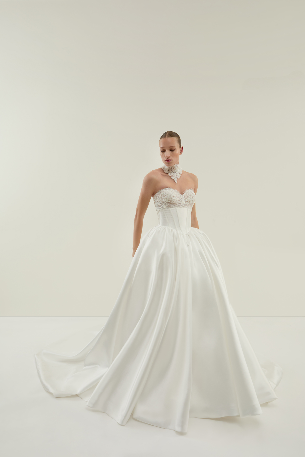Frau mit ruhigem Blick im weissen Brautkleid mit Spitzenchoker